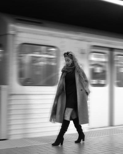 A girl walking in the subway with train blurring hebind